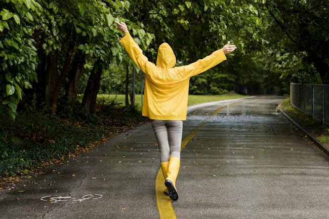 Vrouw in gele regenjas geniet van frisse lucht tijdens dagelijkse wandeling buiten