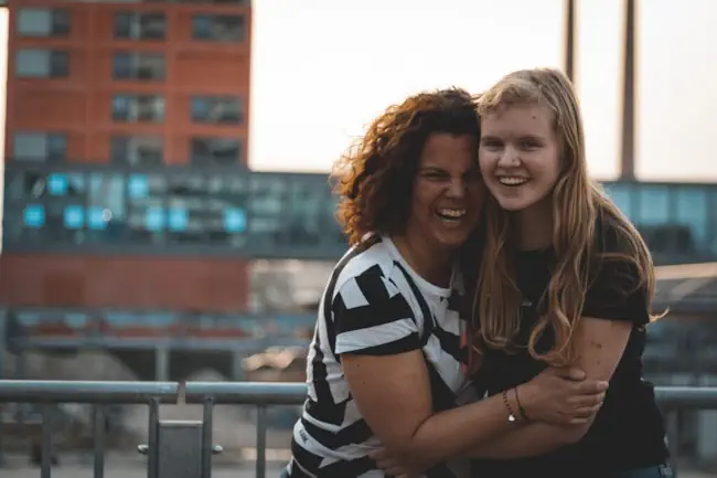 Moeder en dochter lachen en omarmen elkaar – symbool voor verbinding, familielijnen en verandering door systemisch werk