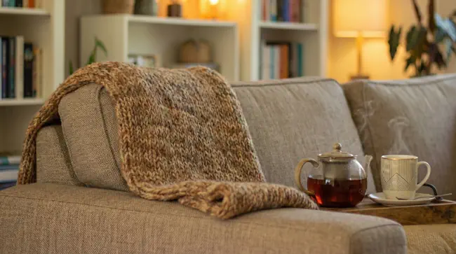 Warme bank met deken en thee als veilige plek tijdens trauma in december, passend bij Mieke Loor.