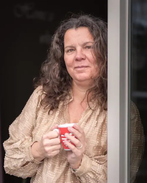 mieke-loor-contactpagina-jouw-eigen-veerkracht Mieke Loor met een kop thee bij de deur van haar praktijk Jouw Eigen Veerkracht