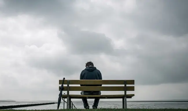 Man zit alleen op bank aan zee en voelt zich eenzaam en depressief – therapie bij Mieke Loor Jouw Eigen Veerkracht